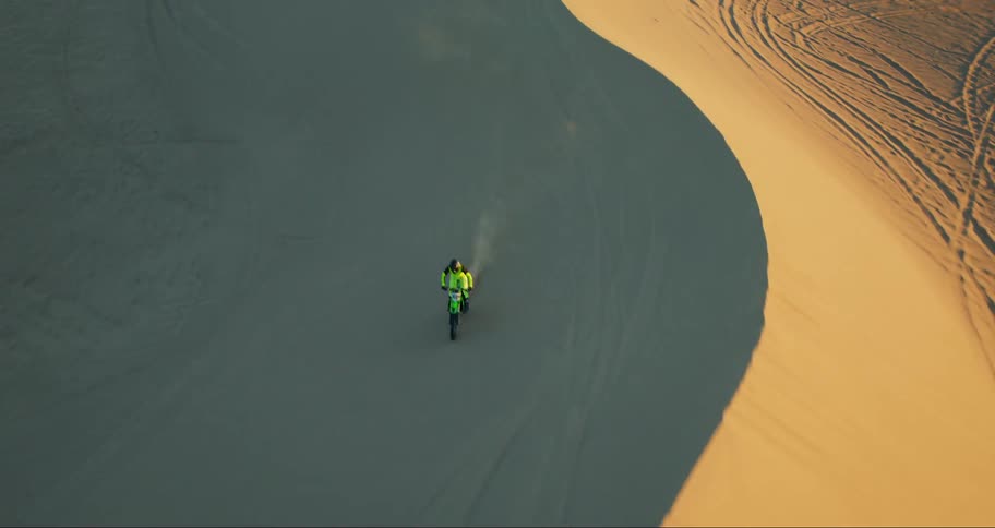 Two motorbikes ride over the dunes