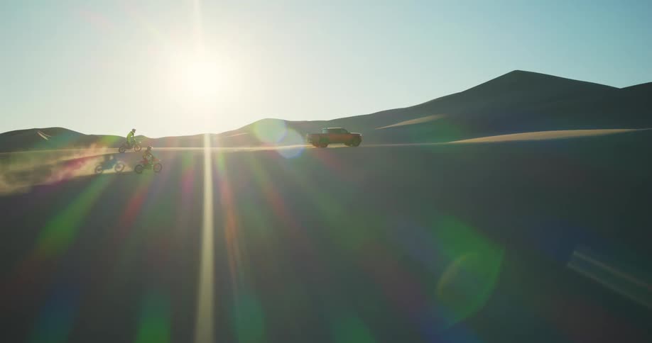 Two motorcycles and a pickup truck traveling through the desert dunes