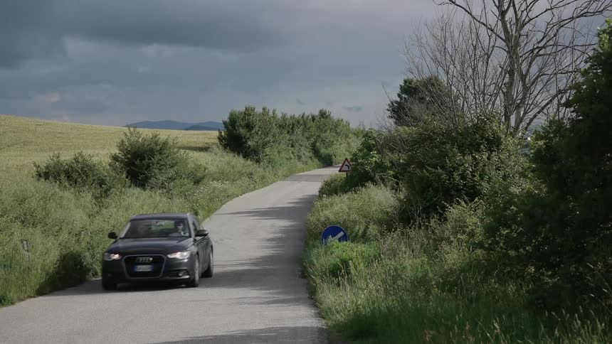 A black car drives down a small paved road