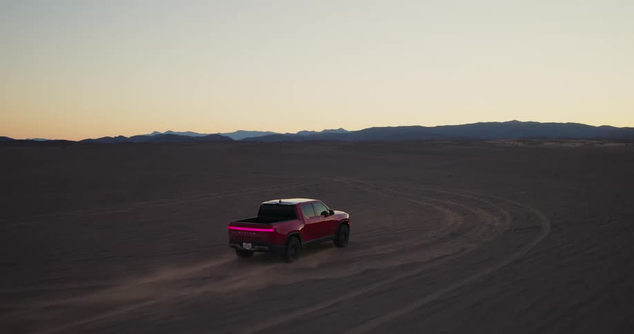 A red pickup truck driving in a desert region