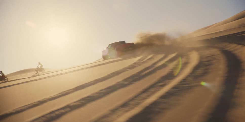 Two motorbikes and a car are driving in a desert and kicking up a lot of sand as they skid