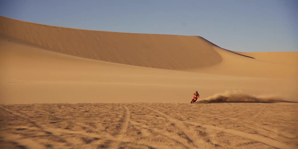 Person with motocross high speed meeting through desert dunes