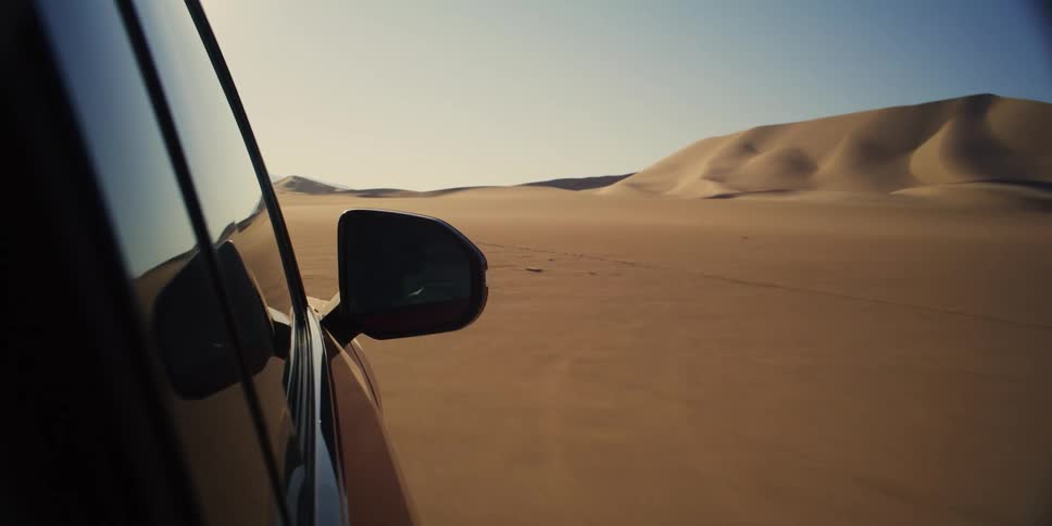 Car moving through desert sands during cloudless day
