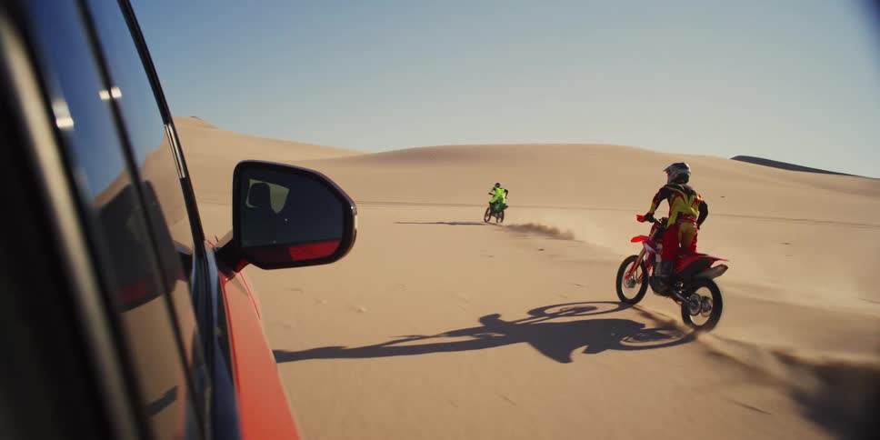 Two people on motocross at high speed through the desert