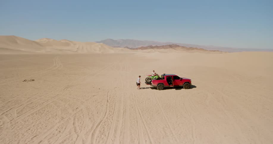 A footage of people packing up some belongings into the truck in the desert