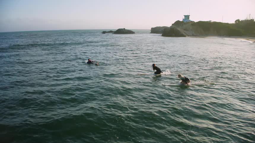 Aerial of surfers catching waves on a beach during a sunny day