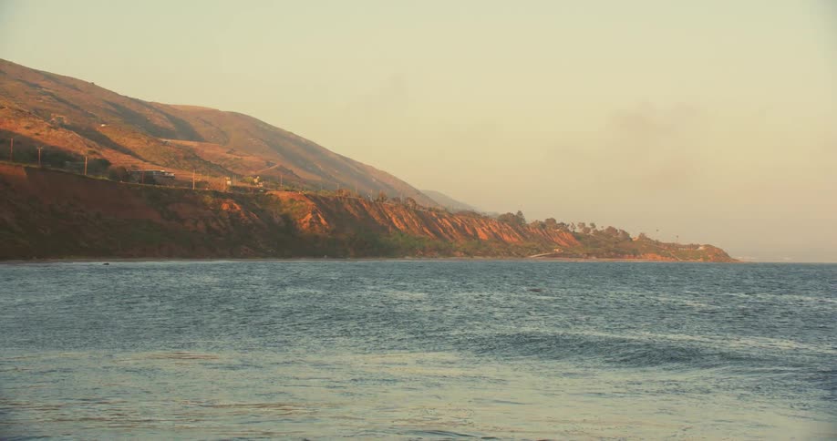 Aerial of the mountainous coast of a beach at sunset