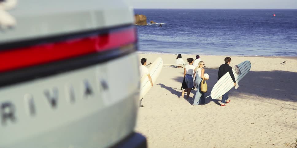 A group of people with surfboards are walking on the beach towards the ocean