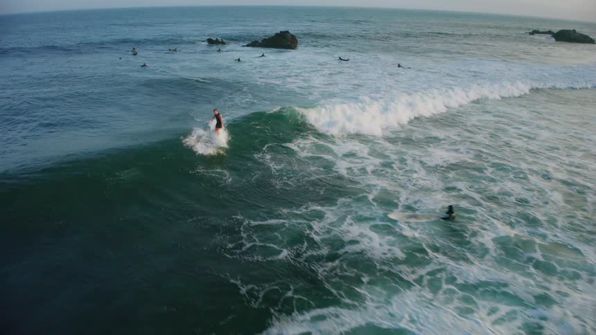 A person is catching a wave and surfing it and there are several other surfers in the water