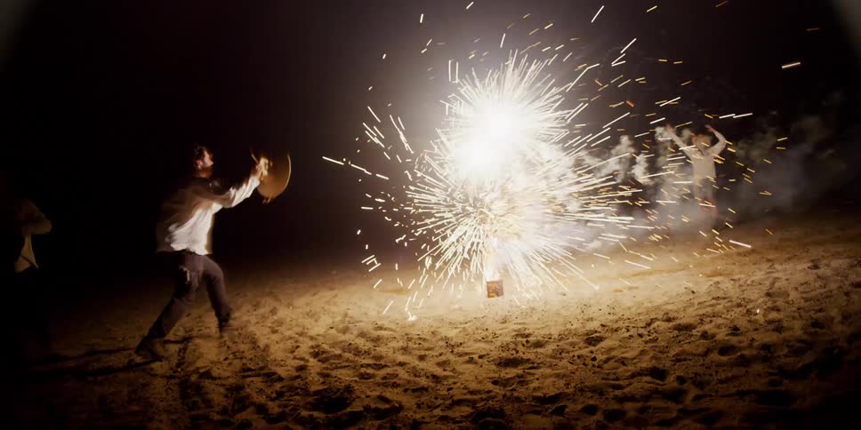 People run around the fireworks on the beach
