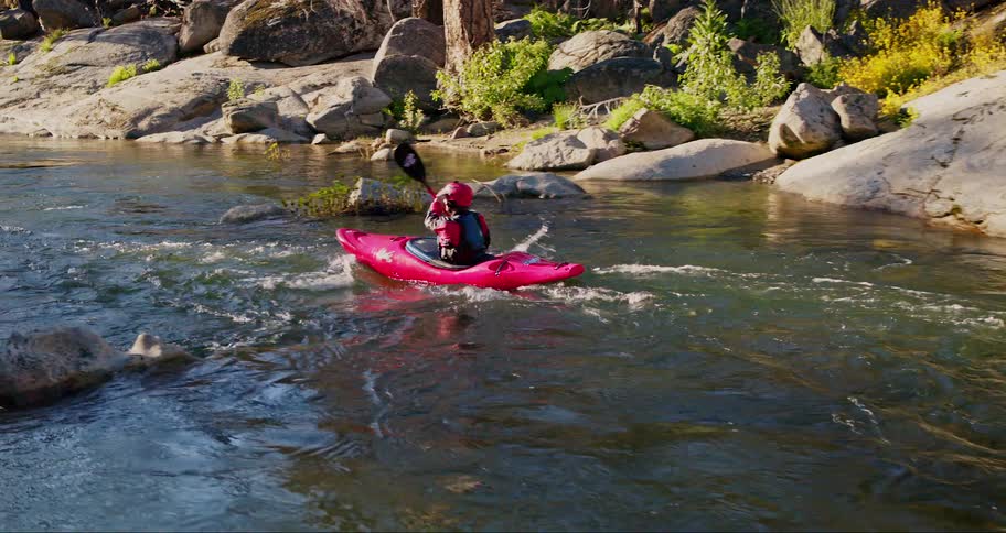 A person in a red kayak is navigating through a rocky river