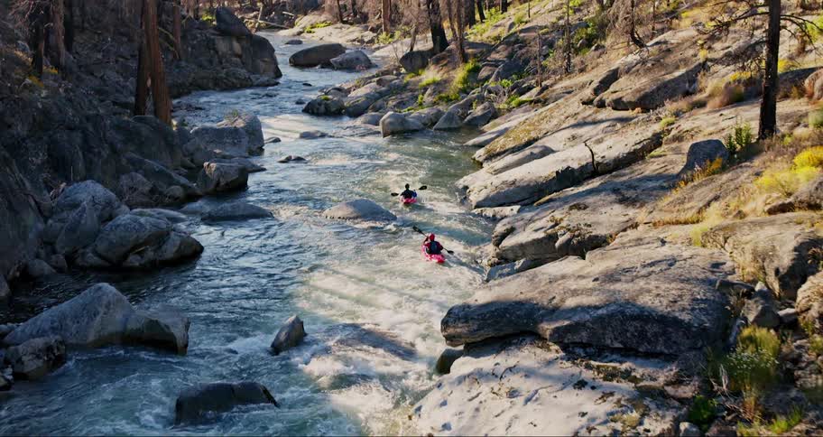 Two kayakers navigate a river rapid