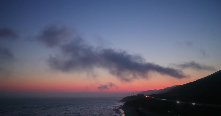 Low clouds hang over the coast on a colorful sunset sky