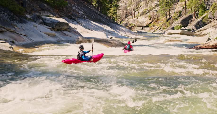 Two people kayak down a river