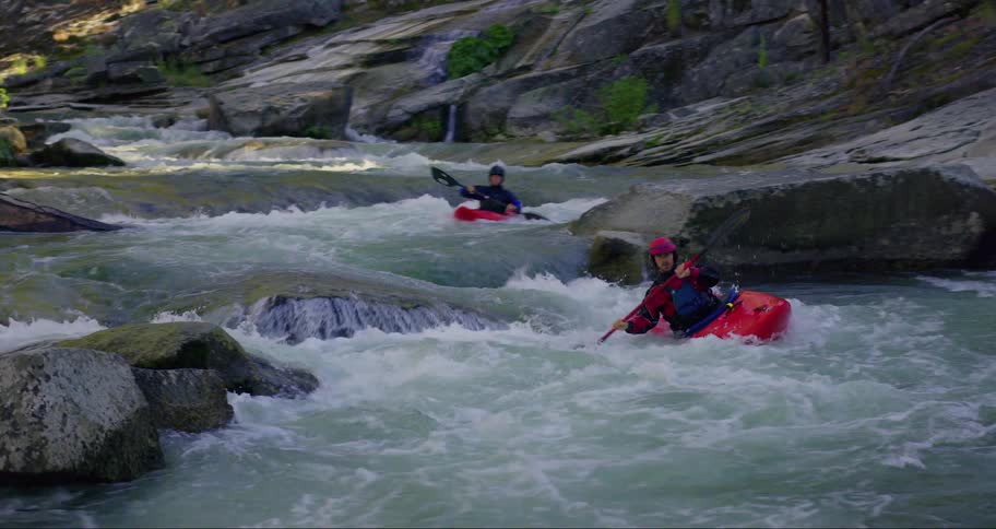 Two people kayaking down rapids in a river