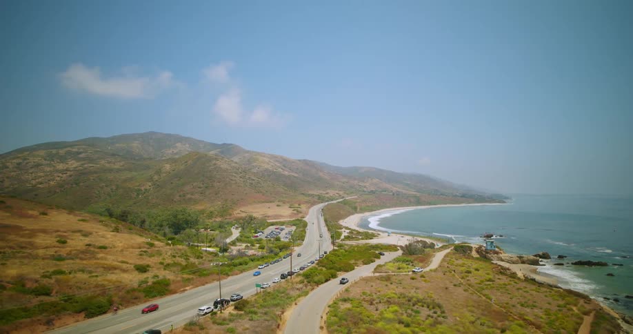 A car driving on a street next to a beach
