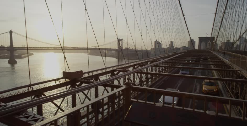 Vehicles travel down a city bridge on a sunny day
