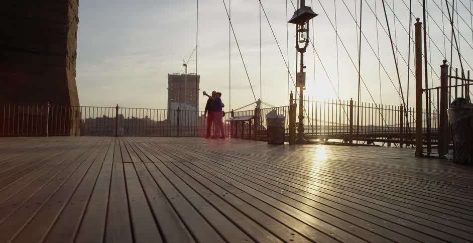 People standing on a boardwalk at sunset