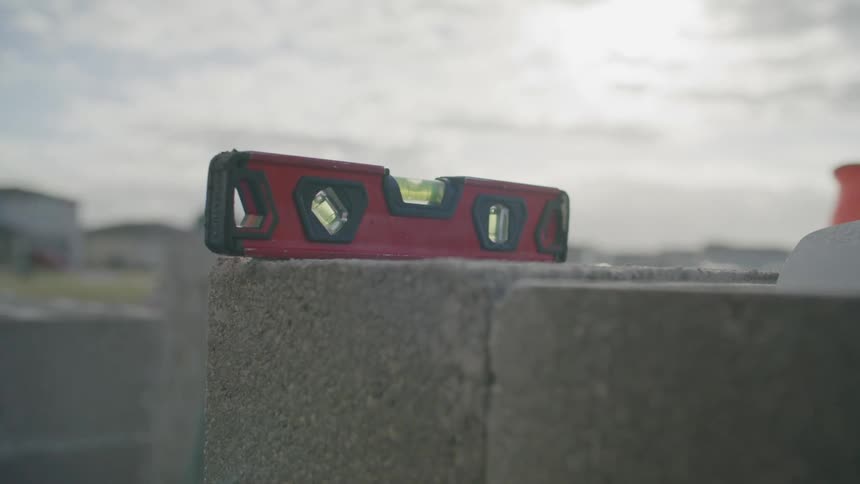 A person resting a tool on top of concrete bricks at a construction site