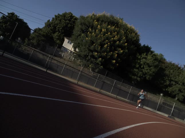 A young man runs on a race track in slow motion