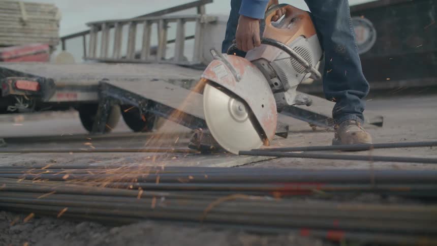 A person is holding a saw and cutting a steel material