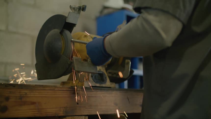 A worker uses a grinder on a piece of metal