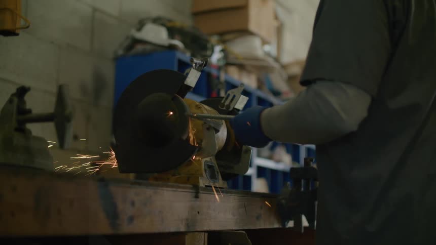 A man is using a angle grinder in the shop
