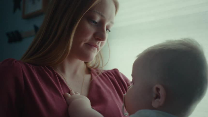 Mother holds baby while near window