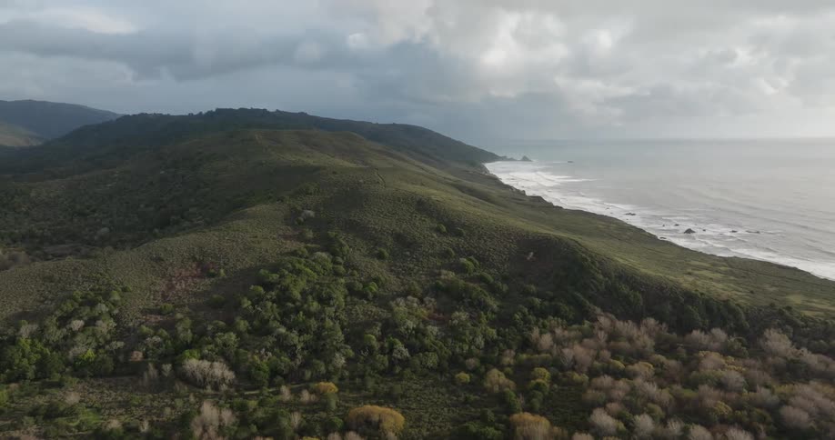 Landscape of a peninsula with hills and mountains next to the sea on a clear day with clouds