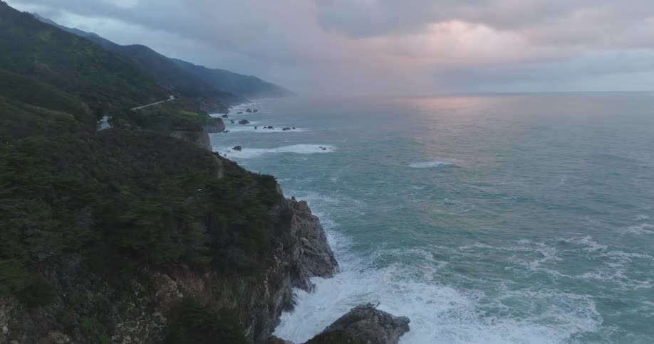 Aerial of the mountainous coast of an island during a cloudy sunset