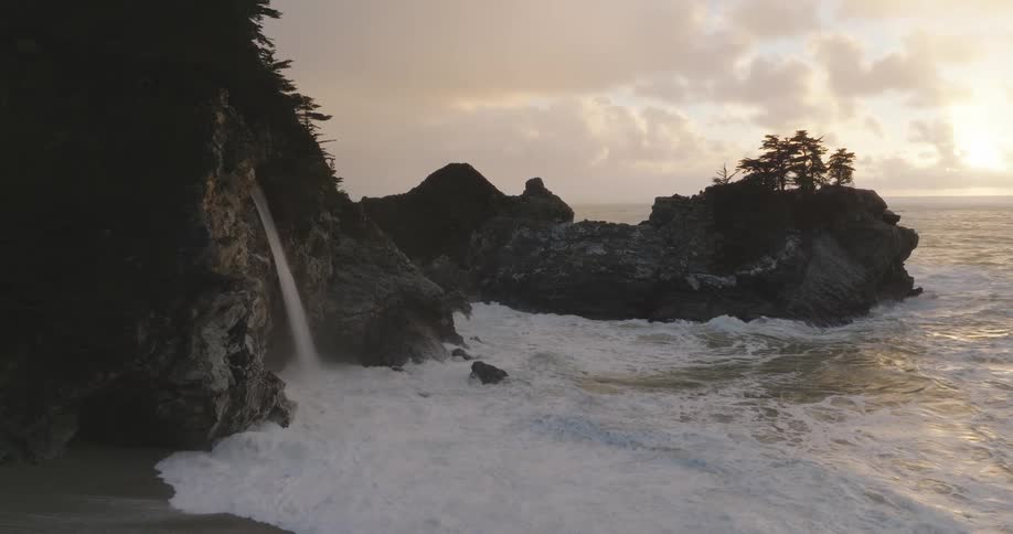 Waves come ashore near a small waterfall