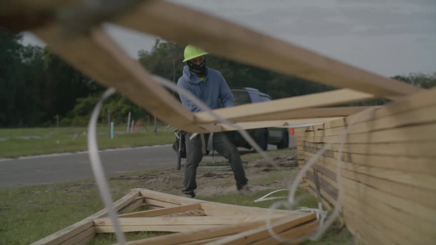 Men carry lumber frames on the work site