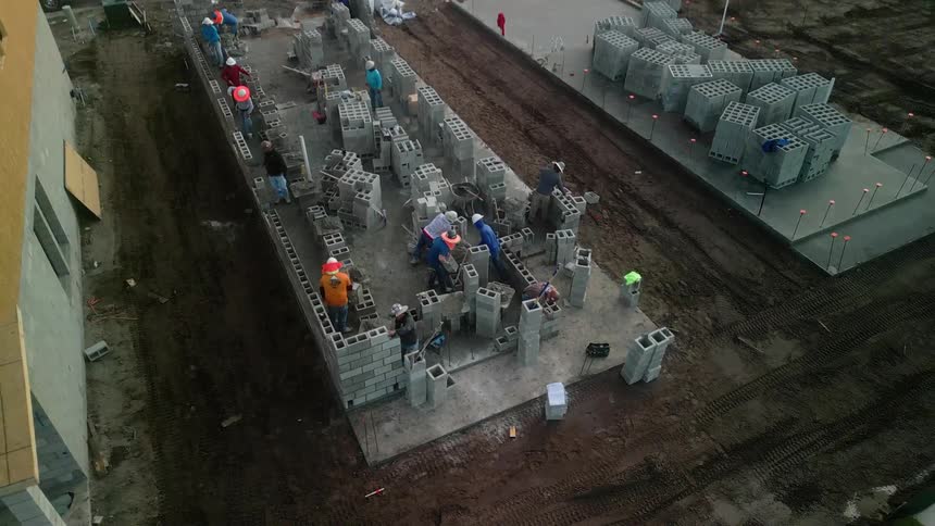 A group of construction workers build a wall