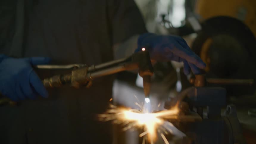 Man with protective mask carrying out welding causing sparks to come out