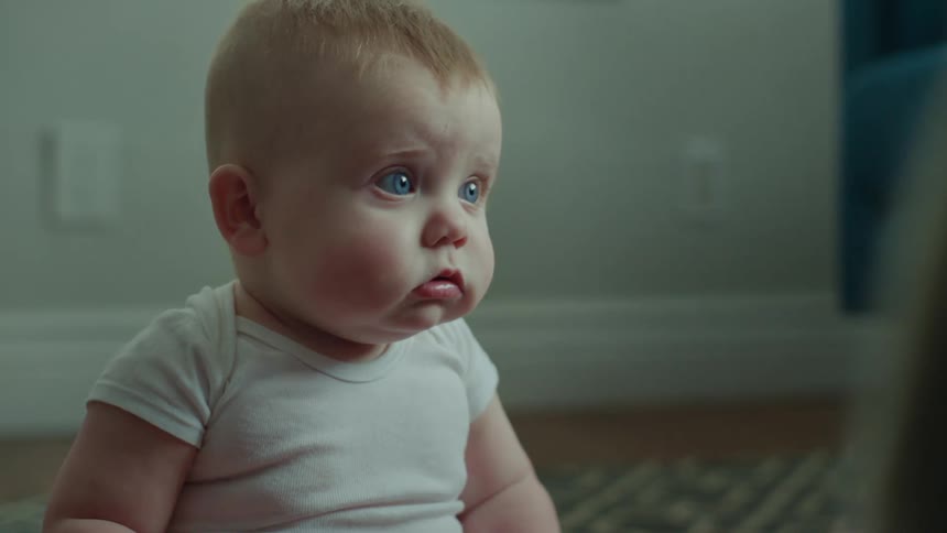 Close up of a baby with blue eyes sitting on the floor