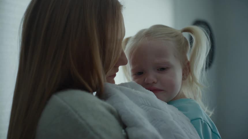 A mother rocks her crying daughter