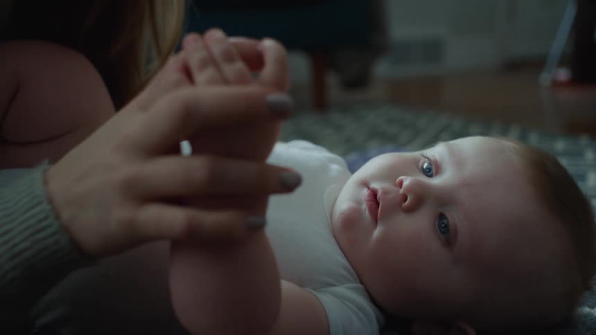 A mother is touching her babies hands