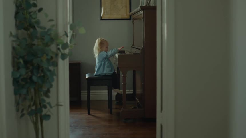Little little child sitting in front of the piano and playing