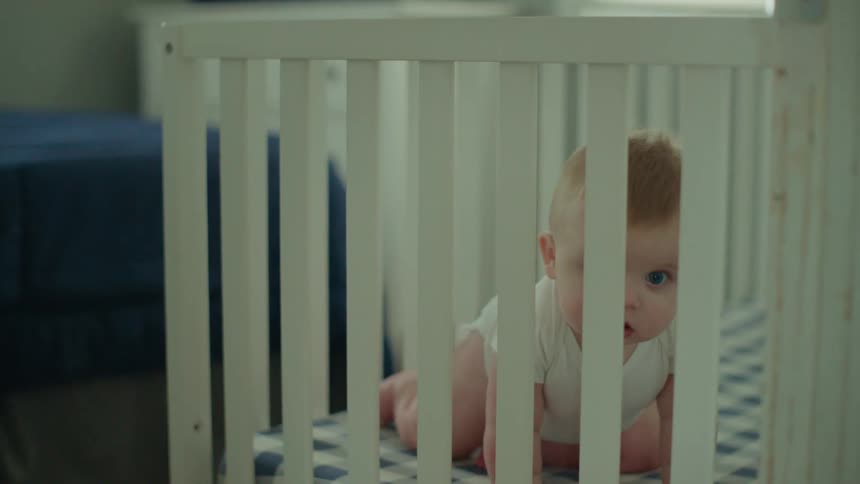 A baby crawls in a crib