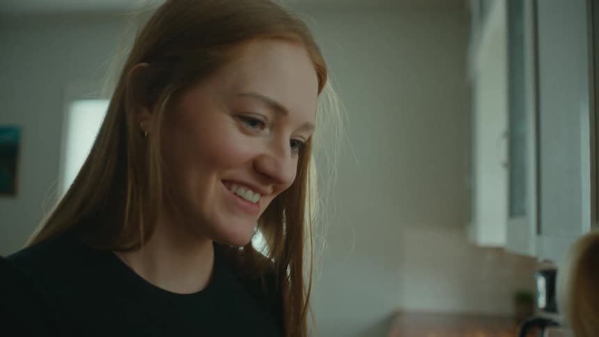 Happy mother talks to her baby daughter in the kitchen
