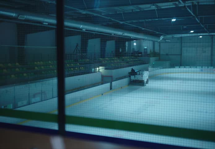 A person uses a ice cleaning zamboni machine on an ice rink