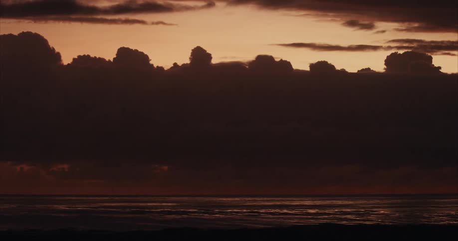 A peaceful and beautiful sunset scene over the water with silhouetted clouds