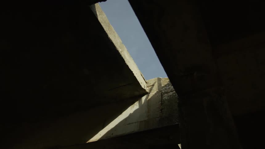 Sun shines below concrete structure through gap