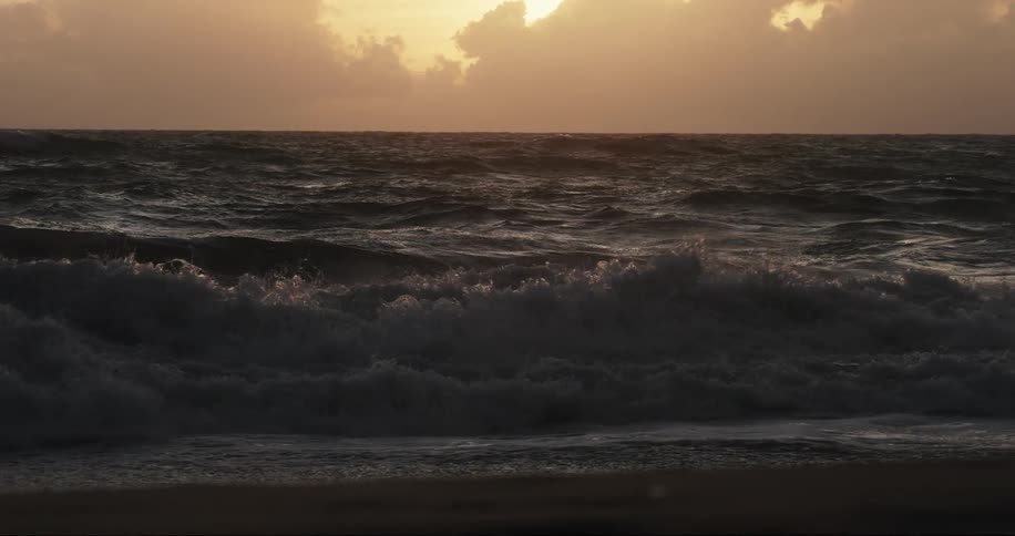 Sea landscape with waves in slow motion in a sky with a sun on the horizon