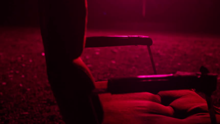 A chair sits outside at night bathed in pink light