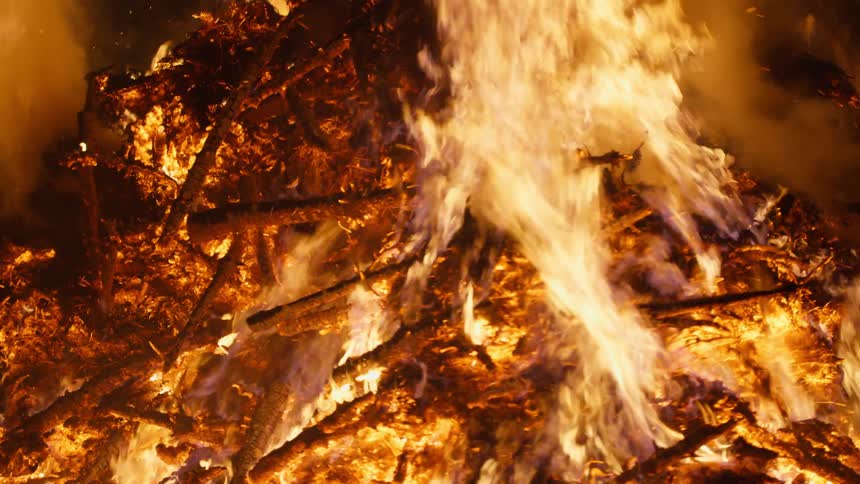A bonfire with bright flames consuming wooden logs and branches