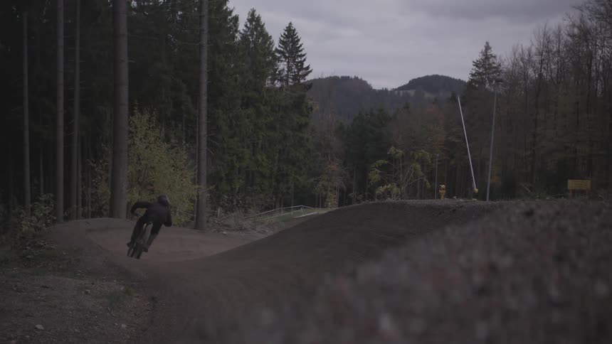 A bicyclist rides a dirt course in the woods