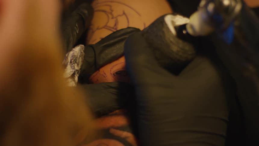 Tattoo artist performing a tattoo on a persons skin