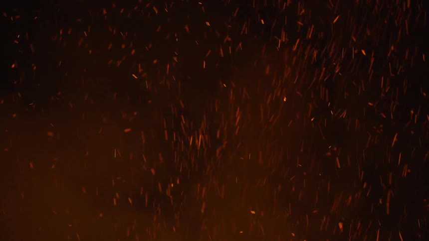 Sparks rise as a blazing fire burns in the darkness