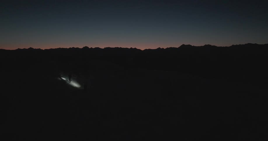 A person with a flashlight climbs a slope